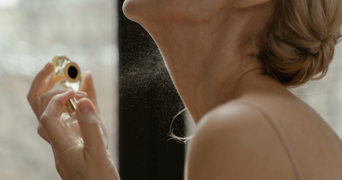 woman spraying scent on her neck as part of her body care routine